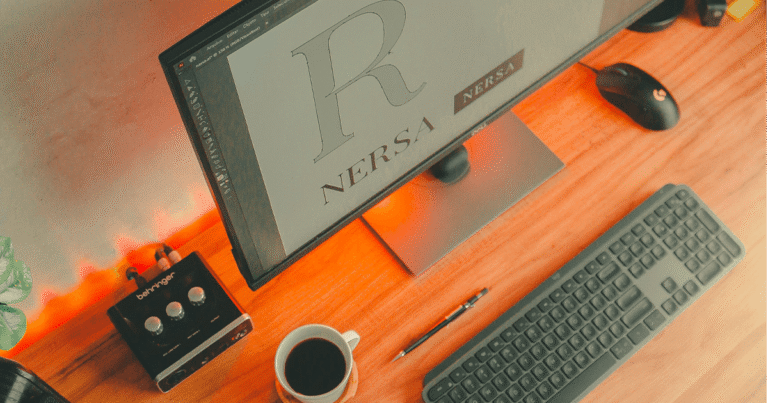 Mesa de trabalho organizada com monitor, teclado, mouse e uma xícara de café, ilustrando como um espaço limpo ajuda a melhorar a concentração no home office.