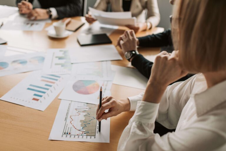 Profissionais realizando uma reunião em um ambiente corporativo com documentos e gráficos sobre a mesa
